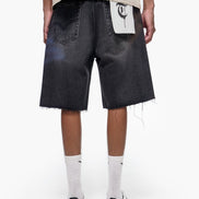 Person wearing black denim shorts with a white logo on a white background