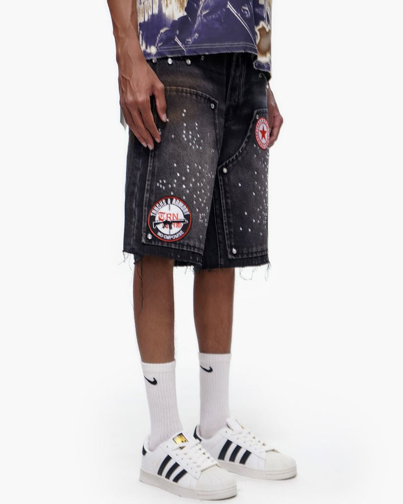 Person wearing a black denim skirt with patches, white socks, and white sneakers on a white background
