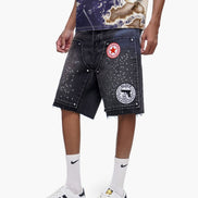 Person wearing denim shorts with patches and a graphic t-shirt on a white background