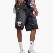Person wearing black denim shorts with patches and logos, white sneakers, and a colorful shirt.