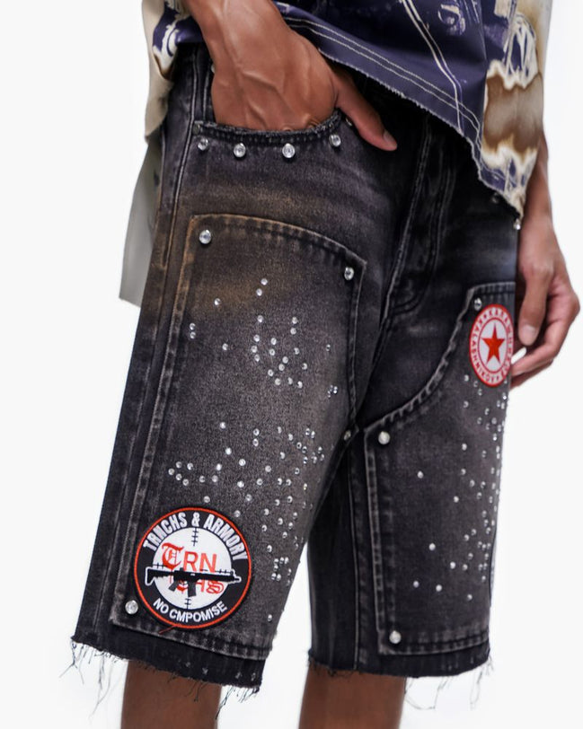 Black denim shorts with patches on a white background