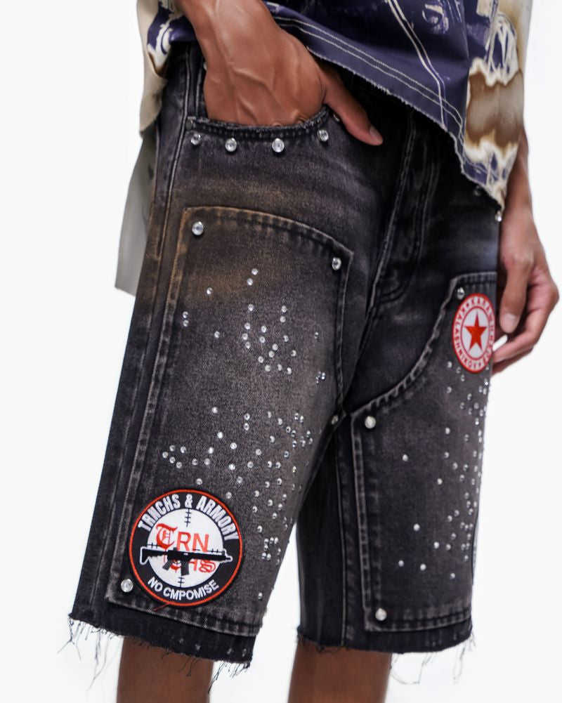 Black denim shorts with patches on a white background