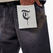 Person wearing black jeans with a white label featuring a logo in the pocket.