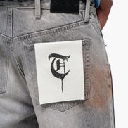 Gray jeans with a white patch featuring a black letter 'T' on a white background