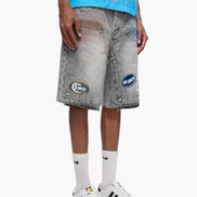 Person wearing gray denim shorts with brand logos, white sneakers, and light blue shirt on a white background