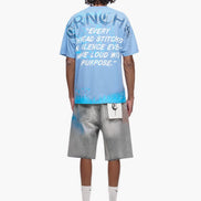 Person wearing a blue t-shirt with text and gray shorts on a white background
