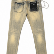 Back view of light-wash denim jeans with a faded yellow-tan wash, black back pocket patches, and a silver chain accessory attached to the back waistband, shown on a white background.