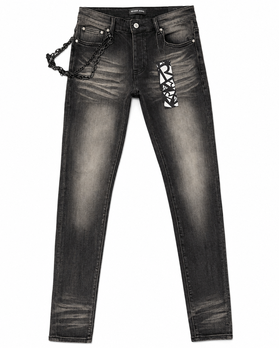 Black washed denim jeans with a decorative black chain hanging from the right pocket and a black-and-white geometric patterned patch on the left thigh, shown against a plain white background.