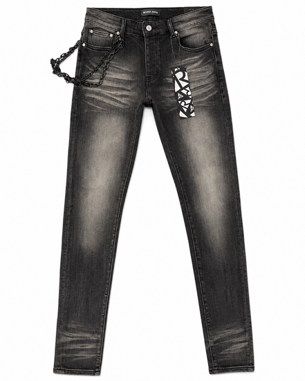 Black washed denim jeans with a decorative black chain hanging from the right pocket and a black-and-white geometric patterned patch on the left thigh, shown against a plain white background.