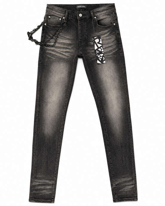Black washed denim jeans with a decorative black chain hanging from the right pocket and a black-and-white geometric patterned patch on the left thigh, shown against a plain white background.