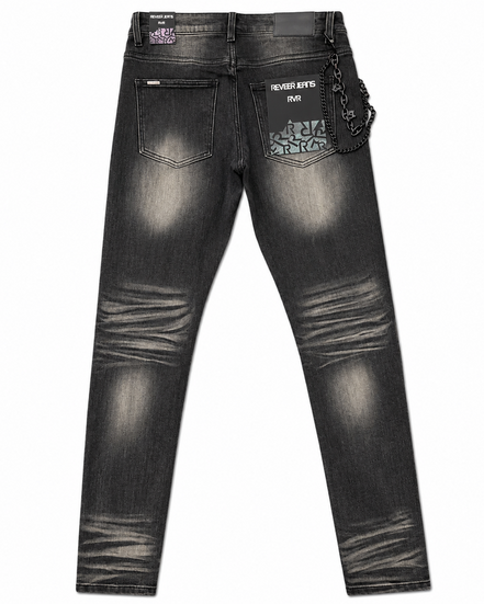 Back view of a pair of dark gray washed denim jeans with distressed fading, featuring a patterned patch pocket on the right side with the text 'NEVER KITS PACK' and a hanging chain detail.