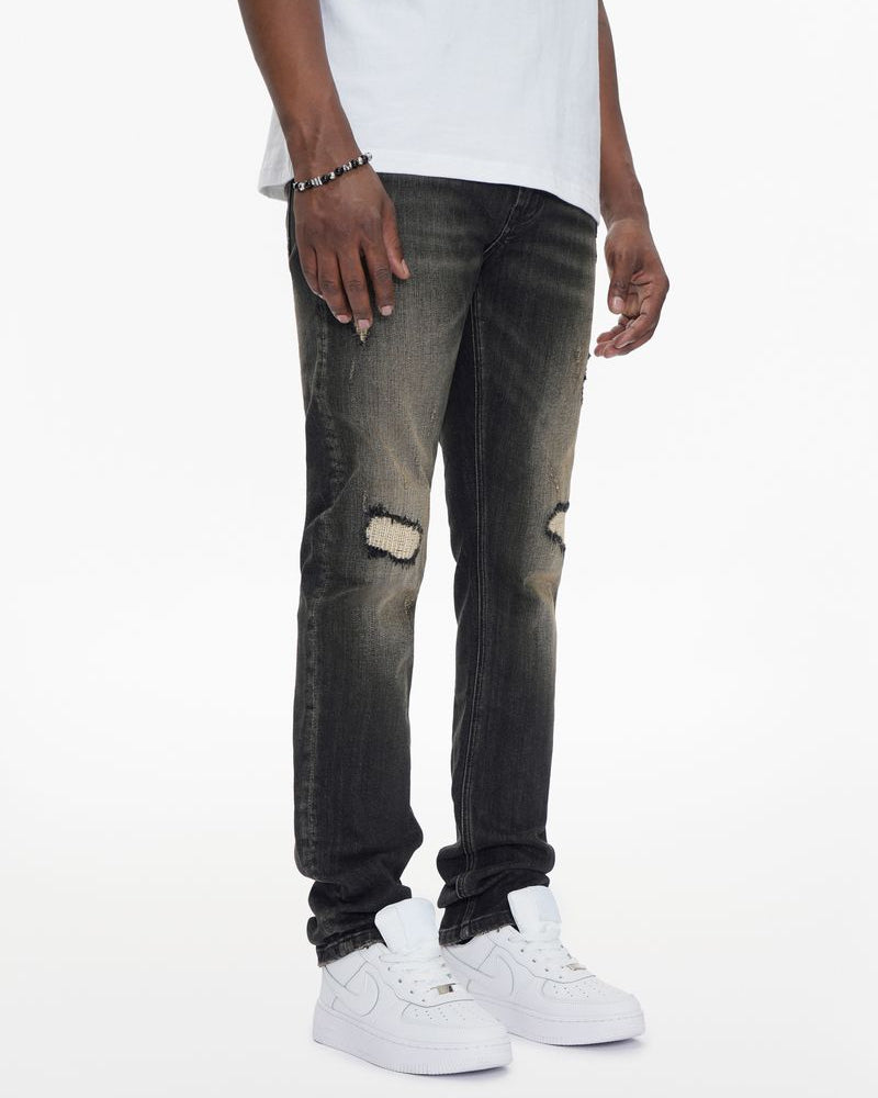 Person wearing distressed black jeans and white sneakers on a white background