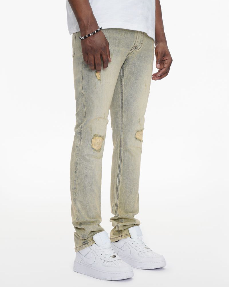 Person wearing light-colored distressed jeans and white sneakers on a white background