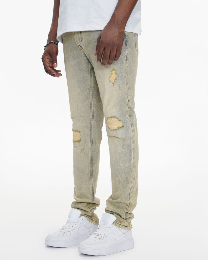 Person wearing light-colored distressed jeans and white sneakers on a white background