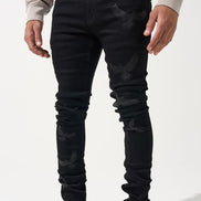 Person wearing black distressed jeans and black and white sneakers on a white background