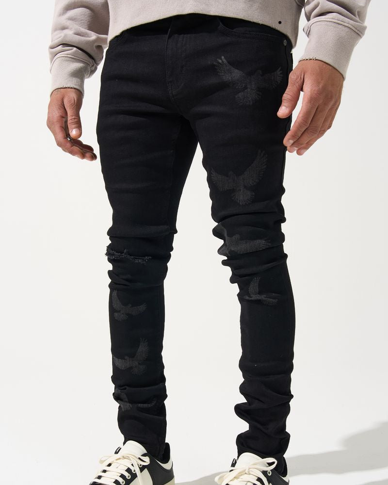 Person wearing black distressed jeans and black and white sneakers on a white background