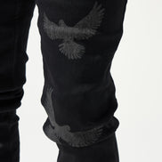 Black jeans with eagle embroidery on a white background