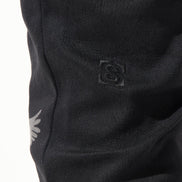 Close-up of black pants with a logo on a white background