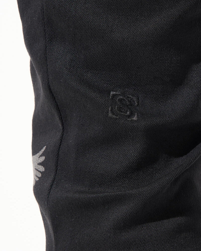 Close-up of black pants with a logo on a white background