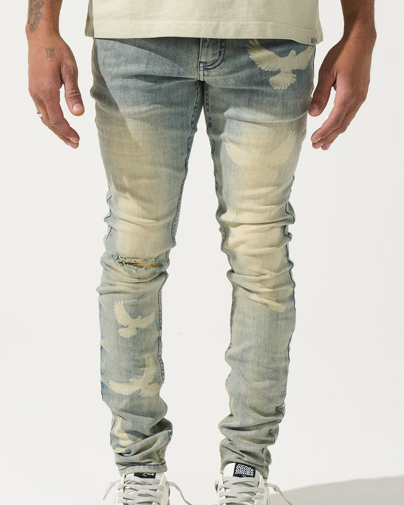 Person wearing light blue distressed jeans and white sneakers on a plain background