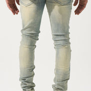 Person wearing light blue jeans and black sneakers on a white background