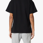 Person wearing a black t-shirt and gray pants on a white background