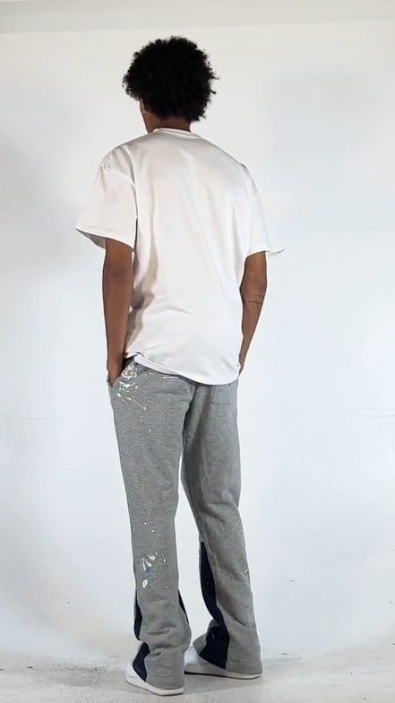 Person wearing a white t-shirt and gray pants with black accents on a white background