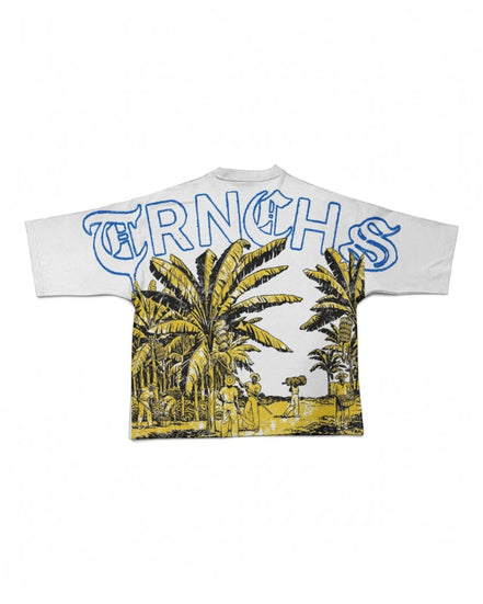 A white short-sleeve t-shirt featuring a large graphic print on the back. The design includes the word 'TRNCHS' in blue outlined letters across the top, above a yellow and black illustrated scene of palm trees and people walking outdoors.