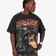A man wearing a black Sublimation brand graphic t-shirt with a skull and mechanical design, paired with camouflage pants, against a light gray background.