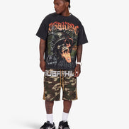 A model wearing a black graphic t-shirt with a red and orange print, matching camouflage shorts with 'SUGARHILL' text, white socks, and black sneakers, standing against a light gray background.
