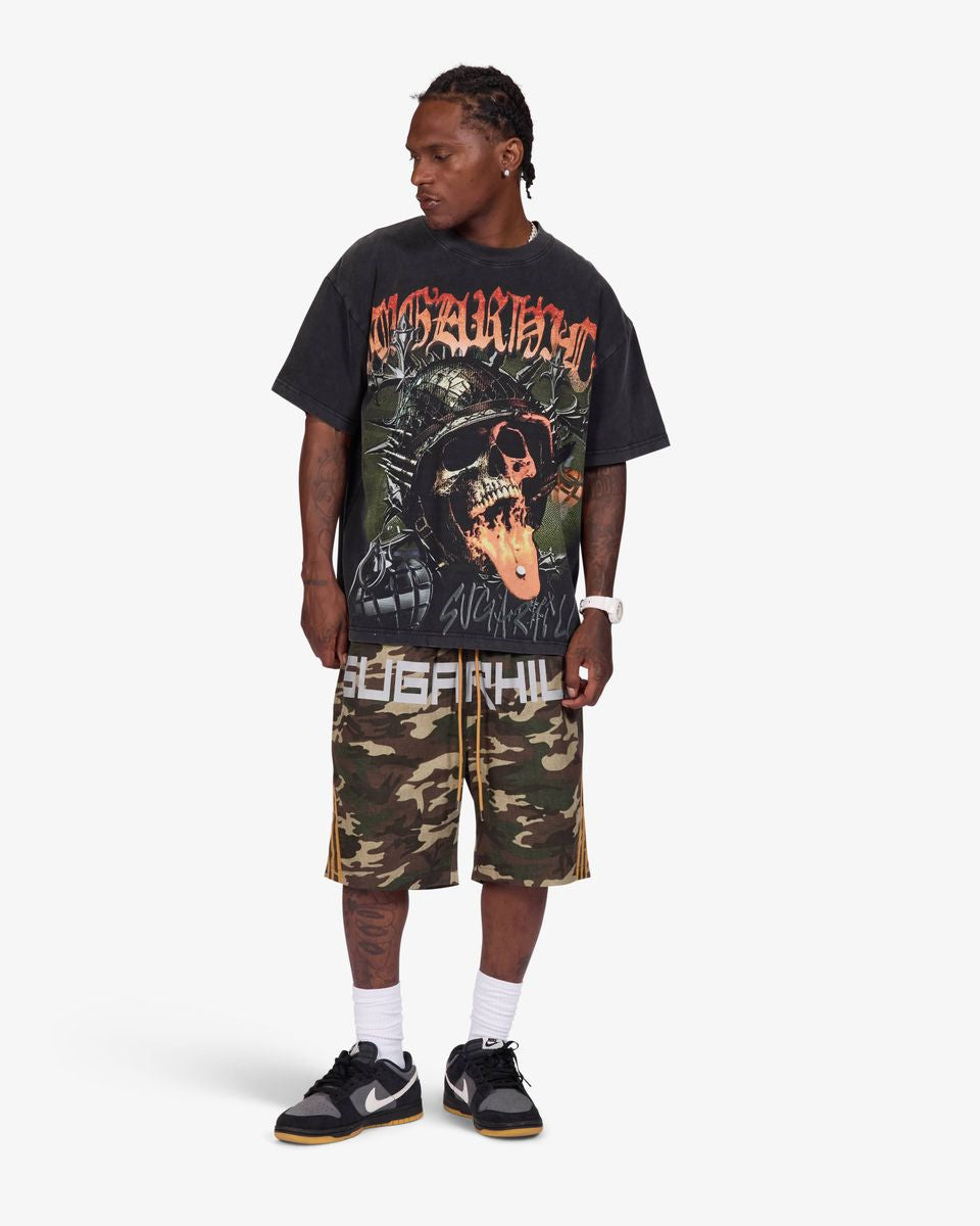 A model wearing a black graphic t-shirt with a red and orange print, matching camouflage shorts with 'SUGARHILL' text, white socks, and black sneakers, standing against a light gray background.