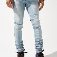 Person wearing light blue ripped jeans and blue sneakers on a white background