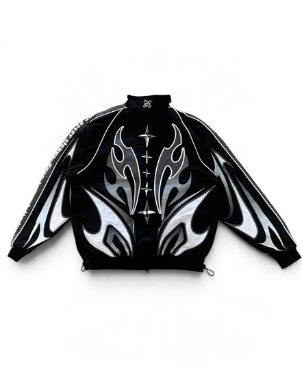 Back of A black zip-up jacket with a high collar, featuring a bold graphic design of white and silver flame-like patterns on the front and sleeves, and a decorative silver cross motif down the center front.