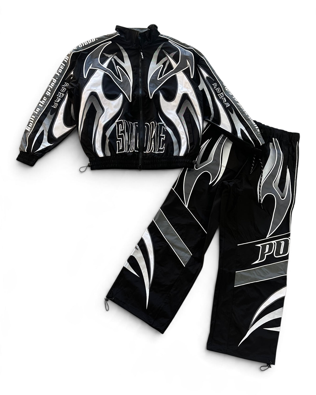 A black two-piece athletic tracksuit featuring a zip-up jacket and matching pants, both decorated with bold silver and white flame graphics and text.
