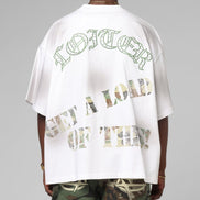 Person wearing a white t-shirt with text on the back, standing against a gray background