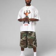 Person wearing a white t-shirt with graphic design and camouflage shorts on a gray background