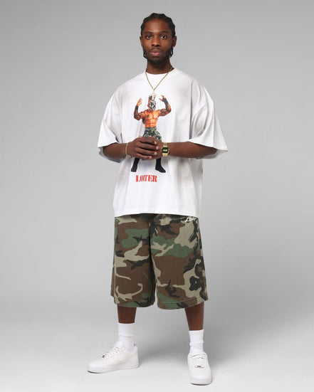 Person wearing a white t-shirt with graphic design and camouflage shorts on a gray background