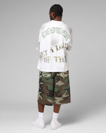 Person wearing a white t-shirt with text and camouflage shorts on a gray background