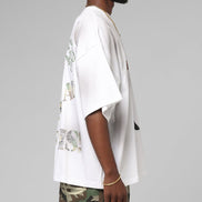 Person wearing a white shirt with camouflage pants on a gray background