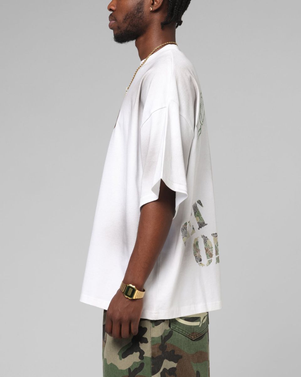 Man wearing a white oversized t-shirt with text and camouflage pants on a gray background