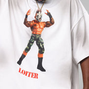 White t-shirt with graphic design of a muscular figure and 'LOITER' text, worn by a person.