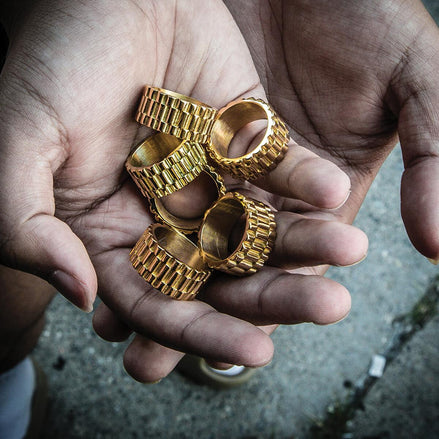 Gold rings with textured design held in a hand against a blurred background