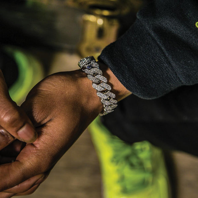 Hand wearing the silver prong cuban link bracelet on a blurred background