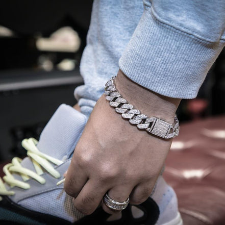 Hand  wearing the silver prong cuban link bracelet on a blurred background