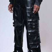 Person wearing black leather pants with multiple pockets and a white background
