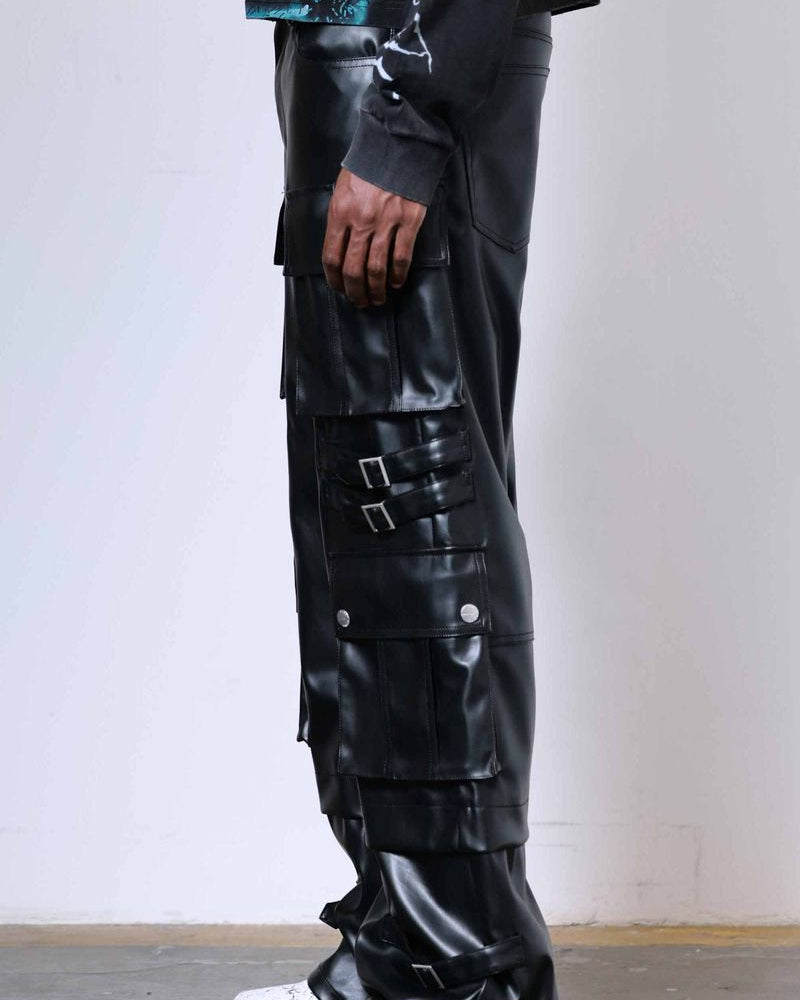 Person wearing black leather pants with multiple pockets and buckles on a plain background