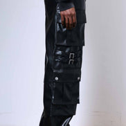 Person wearing black glossy cargo pants with a white background