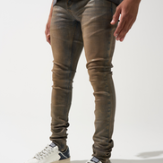 Person wearing brown skinny jeans and white sneakers on a white background