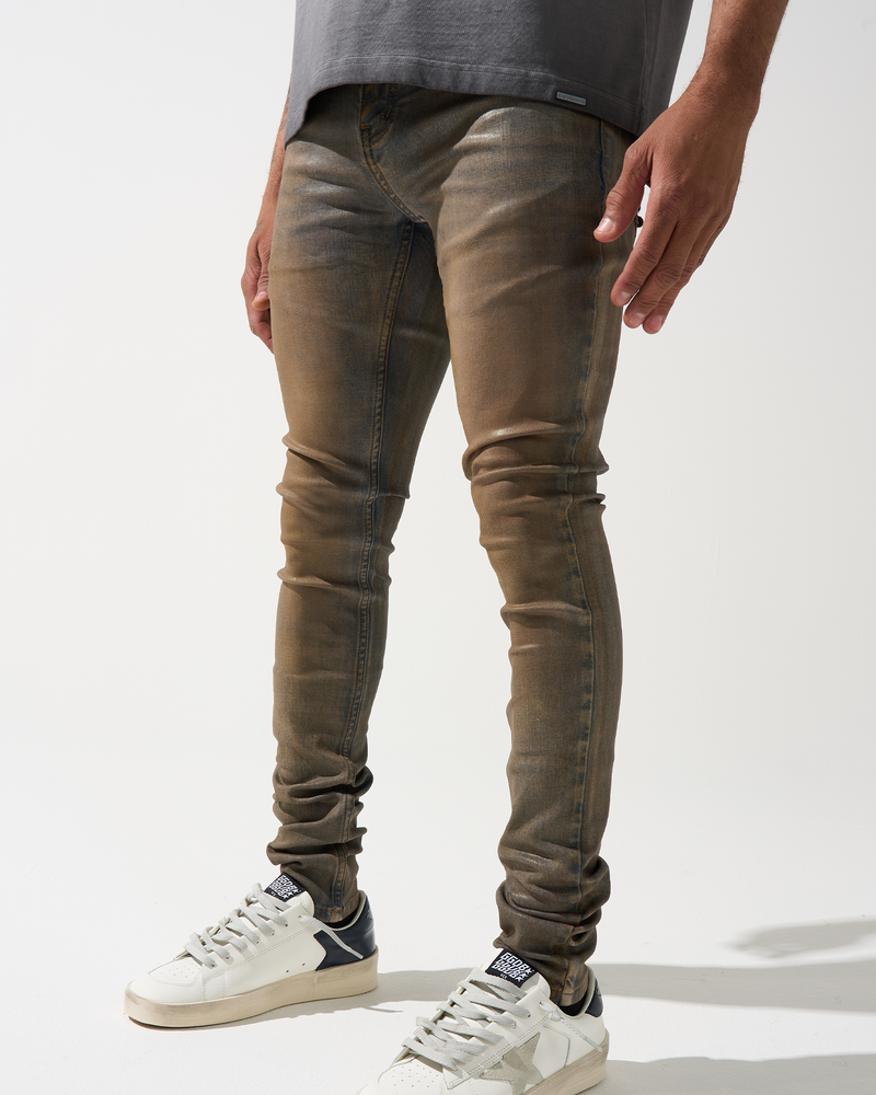 Person wearing brown skinny jeans and white sneakers on a white background