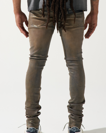 Person wearing brown distressed jeans and white sneakers on a white background